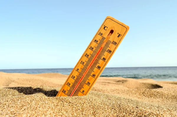 Termometar zaboden u vrući pijesak na plaži prikazuje visoke temperature tijekom toplinskog vala.