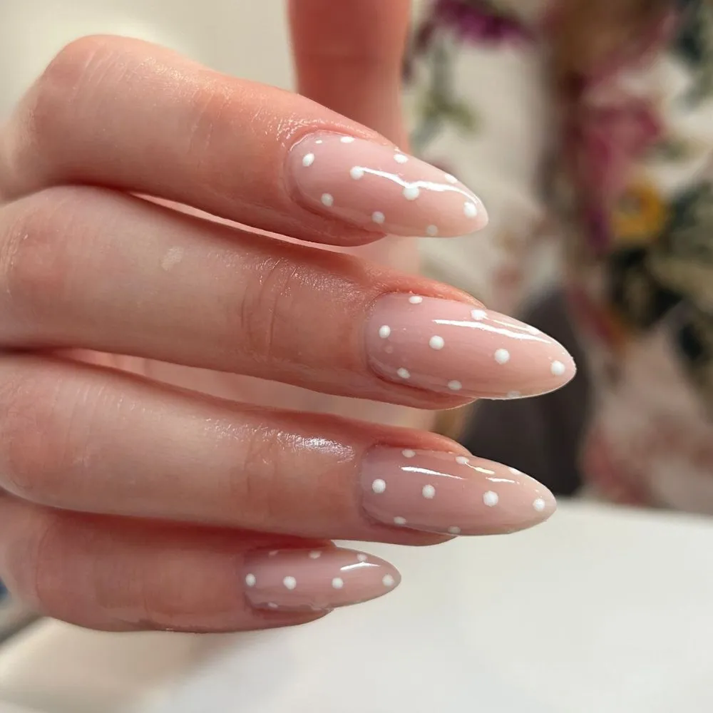 Minimalistički ljetni nail art s nježnim bijelim točkicama na nude podlozi noktiju.